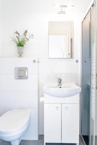 a white bathroom with a toilet and a sink at Willa Bliźniak 2 - Wyżywienie wliczone w cenę in Karwia