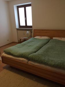 Un dormitorio con una cama con sábanas verdes y una ventana. en Ferienwohnung 3 in Huglfing im Herzen des 5 Seen Land Oberbayerns, en Huglfing 8 fotos más
