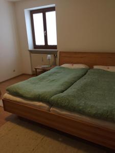 um quarto com uma cama com lençóis verdes e uma janela em Ferienwohnung 3 in Huglfing im Herzen des 5 Seen Land Oberbayerns em Huglfing