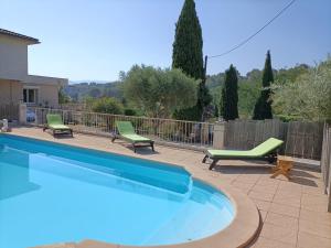 a swimming pool with two lawn chairs and two chairs at gîte en provence in Peypin