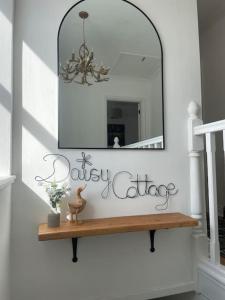 a mirror on a wall with a wooden shelf at Daisy Cottagee in Alyth