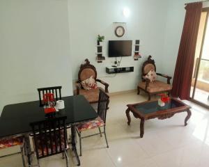 a living room with a table and chairs and a tv at Palolem garden estate in Canacona