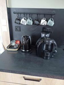Appartement Auzances في Auzances: منضدة سوداء عليها قدور الشاي وصانع القهوة