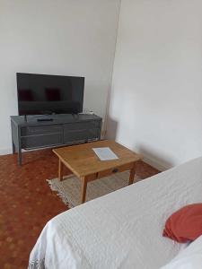 sypialnia z łóżkiem, telewizorem i stołem w obiekcie Appartement Auzances w mieście Auzances