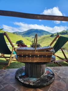 a basket sitting on top of a stump with two chairs at Pousada Vale Monte Azul in Santo Antônio do Pinhal