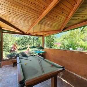 a pool table in a room with a large window at Pousada Vale Monte Azul in Santo Antônio do Pinhal
