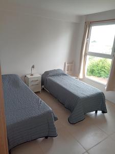two beds in a white room with a window at Departamento Del Valle in Tandil