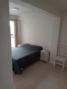 a bedroom with a bed and a chair and a window at Departamento Del Valle in Tandil