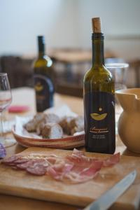 una bottiglia di vino seduta su un tavolo con carne di Rooms&Vinery Bregovi - Sobe in vinska klet Bregovi a Dobravlje