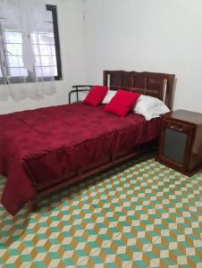 een slaapkamer met een bed met rode lakens en een tafel bij Casa el Nogalito in Tasquillo
