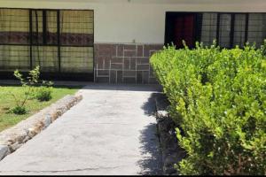 a sidewalk in front of a building with bushes at Casa el Nogalito in Tasquillo
