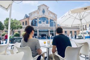 un hombre y una mujer sentados en una mesa frente a un edificio en Desconecta junto al Mercado Central de Alicante, en Alicante