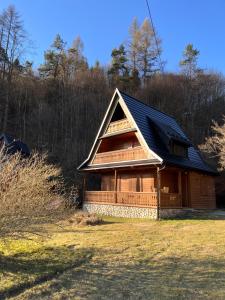 domek z bali z czarnym dachem na polu w obiekcie Drewniany Domek BB Nad Rzeką w mieście Powrożnik