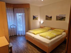 a bedroom with a bed with yellow sheets and a window at Residenz Darianne 12 in Leukerbad