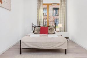 um quarto branco com uma cama com almofadas vermelhas em Old Town Apartment Browar Lubicz Krakow em Cracóvia