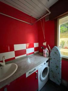 a red bathroom with a washing machine and a sink at Punta Salera house & beach in Pobra do Caramiñal