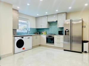 a kitchen with a refrigerator and a dishwasher at 2 Bedroom Flat or Appartment near Heathrow with Garden in Uxbridge