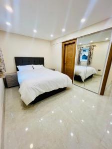 ein Schlafzimmer mit einem großen Bett und einem Spiegel in der Unterkunft 2 Bedroom Flat or Appartment near Heathrow with Garden in Uxbridge