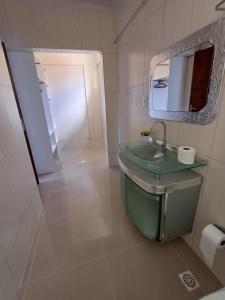 a bathroom with a sink and a mirror at Suíte Atlântica com banheira de hidromassagem in Bombinhas