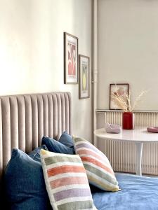 a room with pillows on a bed with a table at Cocon Parisien 12 min Paris - parking privé gratuit - Balcon - Wifi in Enghien-les-Bains