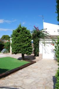 a garden with two trees and a white building at Palomera, Calafat, piscina, frente al mar, a 5 mn de la playa, wifi, zona residencial in Calafat