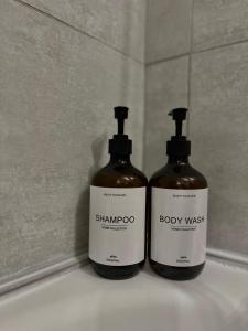 two bottles of shampoo and body wash sitting on a sink at Cocon Parisien 12 min Paris - parking privé gratuit - Balcon - Wifi in Enghien-les-Bains