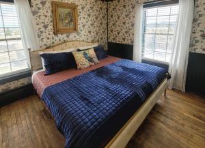 a bedroom with a bed with a blue comforter and two windows at Hand Hotel in Fairplay