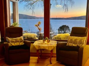 Zimmer mit 2 Stühlen, einem Tisch und einem Fenster in der Unterkunft Villa by the sea, close to the city, with panoramic views in Bergen