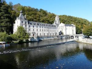 een groot wit gebouw naast een rivier bij La noix qui roule in Champagnac-de-Bélair