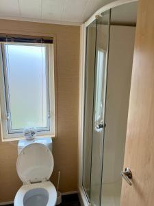 a bathroom with a toilet and a glass shower at Boston Lodge Sunnydale Jubilee way 5 in Saltfleet