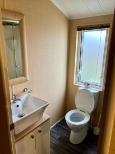 a bathroom with a toilet and a sink and a window at Boston Lodge Sunnydale Jubilee way 5 in Saltfleet