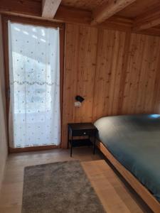 a bedroom with a bed and a large window at La corte Antey Maison De Emilie in Antey-Saint-André