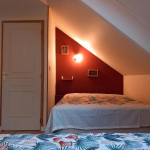 een zolderkamer met een bed en een deur bij gîte le petit roussel in Putanges