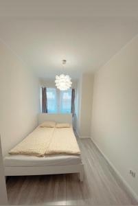 a white bedroom with a bed and a chandelier at Apartament w rynku in Radków