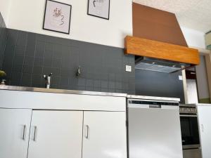 una cocina con armarios blancos y una pared de azulejos negros en La Terasse des Vignes - Maison 2 Chambres - 4 Personnes en Blienschwiller