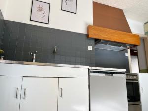 a kitchen with white cabinets and a black tile wall at La Terrasse des Vignes - Gîte 3 Étoiles Centre Alsace - Logement entier in Blienschwiller