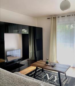 a living room with a table and a television at Cocon Parisien 12 min Paris - parking privé gratuit - Balcon - Wifi in Enghien-les-Bains