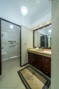 y baño con ducha, lavabo y espejo. en Solymar corner penthouse condo en Cancún