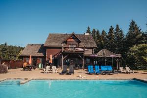 une cabane en rondins avec une piscine, des chaises et une maison dans l'établissement Loft Exécutif CherLieu, à Saint-Faustin–Lac-Carré