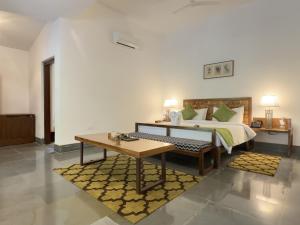 a bedroom with a bed with a table and a bench at Saraca Resort & Spa Corbett in Garjia