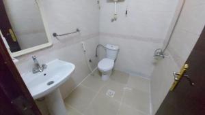 a white bathroom with a toilet and a sink at Jawad Al Dham in Medina