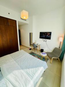 a bedroom with a bed and a chair and a tv at Modern Room With Attached Bathroom Near Rigga Metro & Close to Airport in Dubai
