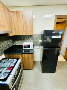 a kitchen with a black refrigerator and a stove at Modern Room With Attached Bathroom Near Rigga Metro & Close to Airport in Dubai