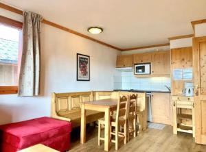 a kitchen with a wooden table and a red couch at Charmant appartement « Les belles roches » Piscine in Notre-Dame-de-Bellecombe