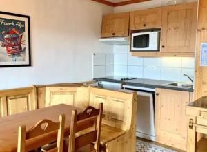 a kitchen with wooden cabinets and a wooden table at Charmant appartement « Les belles roches » Piscine in Notre-Dame-de-Bellecombe