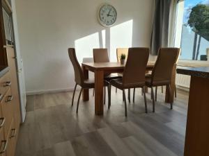 een eettafel met stoelen en een klok aan de muur bij B1- Appartements in Bochum