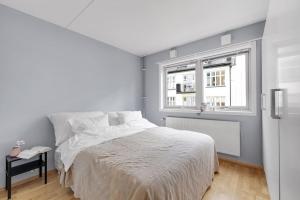 a white bedroom with a bed and a window at Moderne og vakker leilighet, Oslo sentrum in Oslo