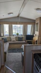 a living room with a large couch and a large window at Floppyfeet Pet Friendly Holiday Home Rental Thornwick Bay, Flamborough in Flamborough
