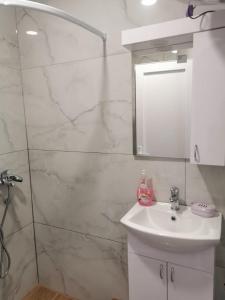 Baño blanco con lavabo y espejo en Apartman Aleksandar 2, en Ribarska Banja
