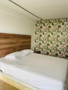 una camera da letto con un letto bianco e carta da parati floreale di FINCA HOTEL TIERRA NUEVA CAMPESTRE a La Vega